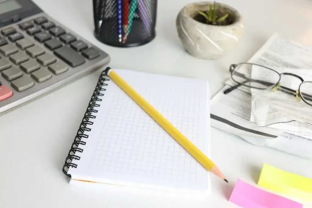 Notebook, calculator, and financial records on a desk for earnings analysis